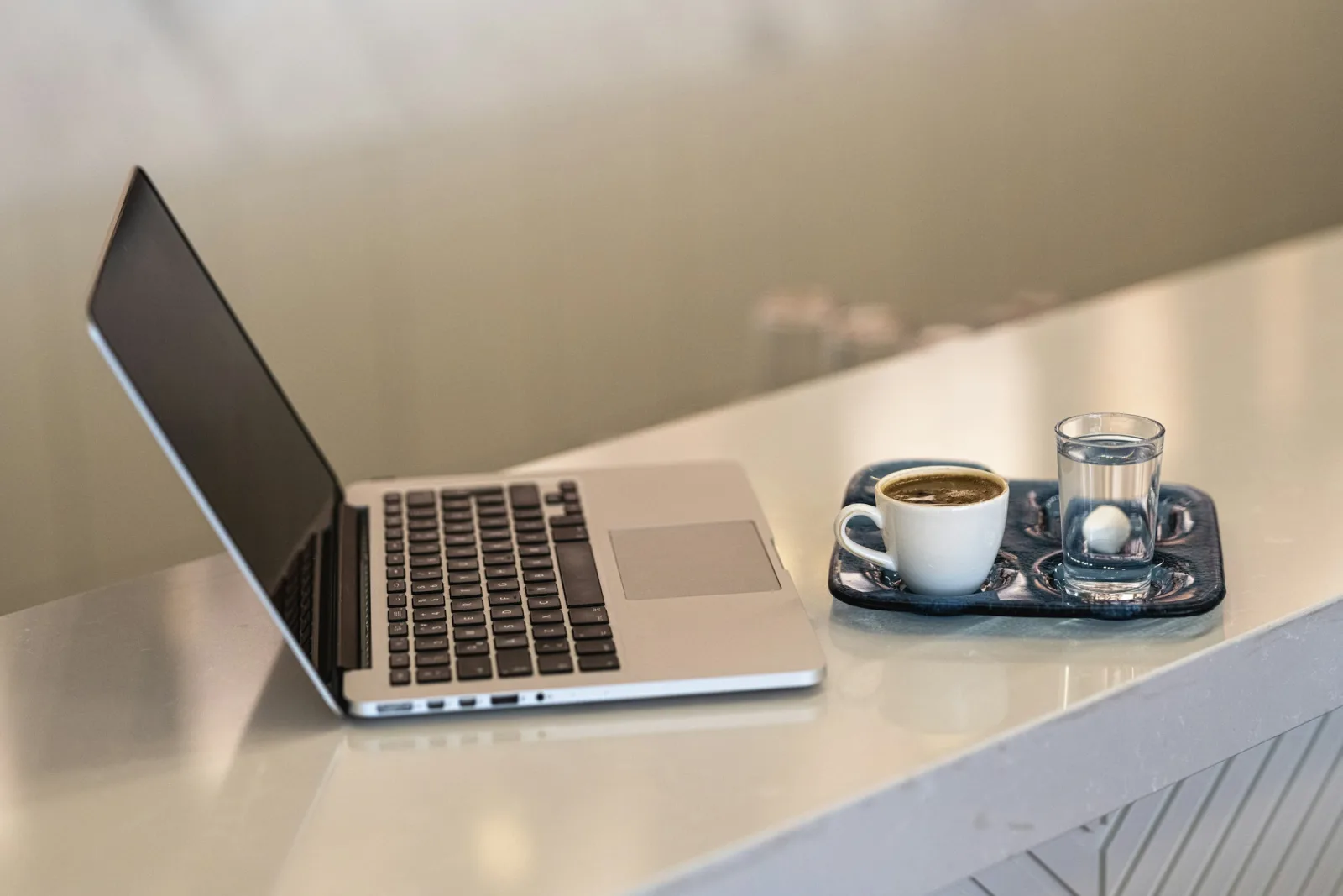 Tách espresso đặt cạnh máy tính xách tay trên bàn làm việc trong phòng khách sạn